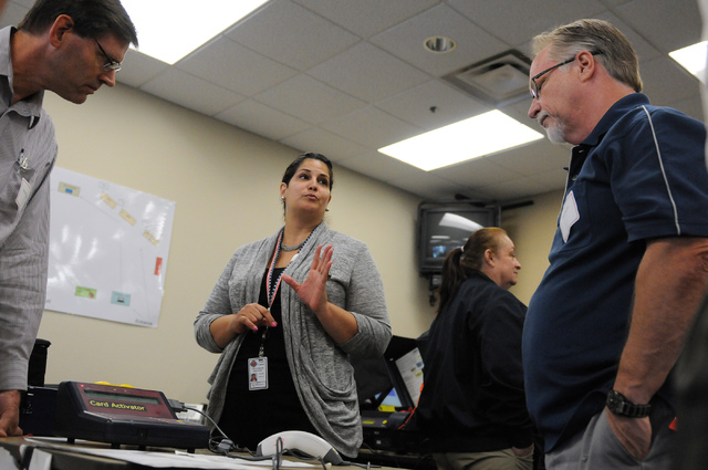 Program assistant instructor Yvette Dallas, center, trains volunteers Todd Myers, right, and Samuel Ingalls about handling poll card activation machines during a poll worker training class at the  ...