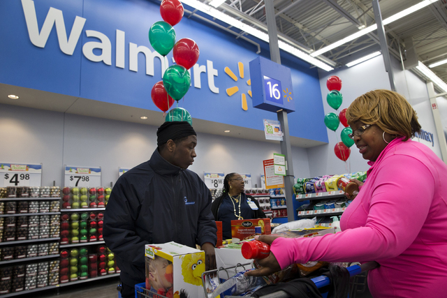 April Taylor, of Upper Marlboro, Md., right, buys items with her son Jarhon Taylor, left, on the opening day of a new Wal-Mart store in Washington. The world's largest retailer on Wednesday, June  ...