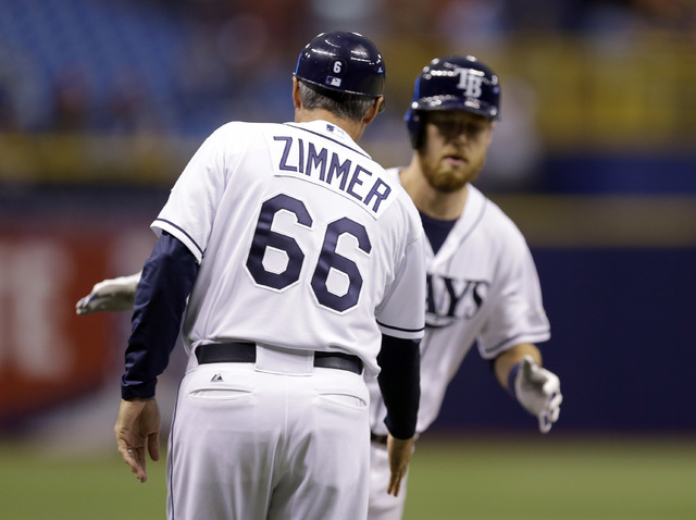 Tampa Bay Rays third base coach Tom Foley, wearing a jersey in honor of senior baseball advisor Don Zimmer, reaches out to shake hands with Ben Zobrist after Zobrist hit a two-run home run off Mia ...