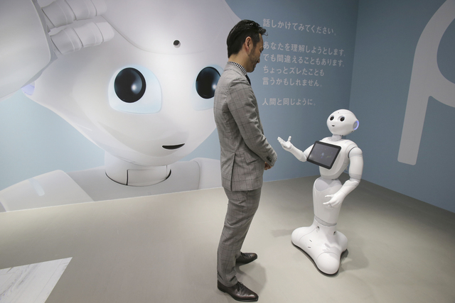 Kaname Hayashi, a project leader of Humanoid Robots "Pepper," talks with the robot at SoftBank Mobile shop in Tokyo, Friday, June 6, 2014. The cooing, gesturing humanoid on wheels that can deciphe ...