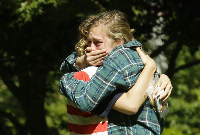 Two women embrace near a prayer circle on the campus of Seattle Pacific University, Friday, June 6, 2014 in Seattle. Classes were cancelled Friday following a shooting at Otto Miller Hall Thursday ...