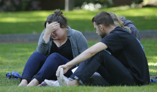 A woman cries as she sits with others near a prayer circle on the campus of Seattle Pacific University, Friday, June 6, 2014 in Seattle. Classes were cancelled Friday following a shooting at Otto ...