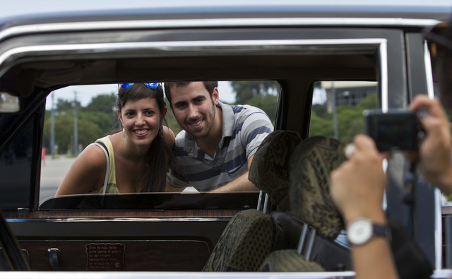 In this June 18, 2014 photo, tourists from Barcelona, Spain take a picture through the window of a Soviet-made limousine taxi cab that was once part of Fidel Castro's fleet in front of Revolution  ...