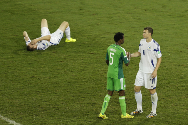 Bosnia's Edin Dzeko shakes hand with Nigeria's Efe Ambrose as Bosnia's goalkeeper Asmir Avdukic sits on the floor during the group F World Cup soccer match between Nigeria and Bosnia at the Arena ...