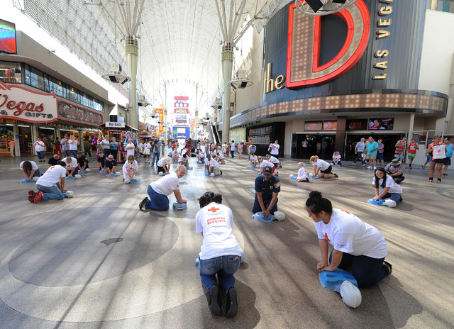Las Vegas Fire Captain Lionel Newby, center right, performs CPR on a manikin while surrounded by American Red Cross volunteers in front of the Third Street stage at Fremont Street Experience in do ...
