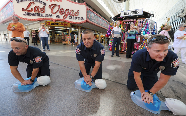 Las Vegas Firefighters, from left, Michael Olivas, David Lopez and Dan Wilder perform CPR on manikins in front of the Third Street stage at Fremont Street Experience in downtown Las Vegas, Friday, ...