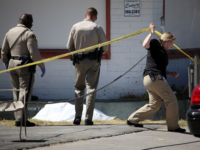 Las Vegas Metropolitan police officers look at a dead body on Third Street in downtown Las Vegas on Wednesday, June 18, 2014. (Justin Yurkanin/Las Vegas Review-Journal)