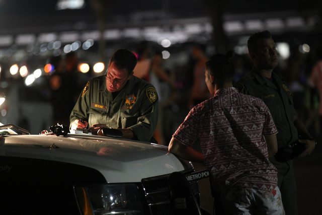 A Las Vegas police officer rights a citation as a man waits outside of the Electric Daisy Carnival at the Las Vegas Motor Speedway in Las Vegas on Friday, June 20, 2014. (Chase Stevens/Las Vegas R ...