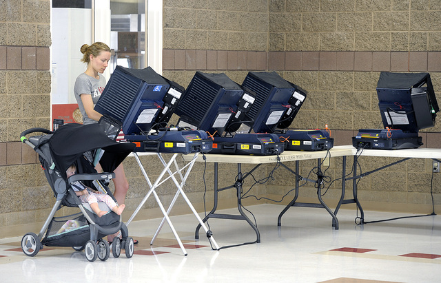 Canella Kircher, accompanied by her 11-month old daughter Sienna, casts her vote in the polling place at Del E. Webb Middle School in Anthem on Tuesday, June 10, 2014. By 8:30am, 29 voters had cas ...