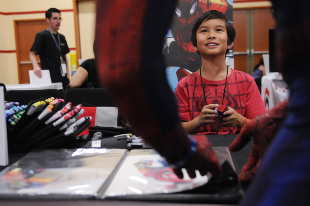Artist Ethan Castillo, 9, speaks with Brett Adams, in character as Spiderman, as he browses his work during the 2014 Amazing Las Vegas Comic Con at South Point casino-hotel in Las Vegas Saturday, ...
