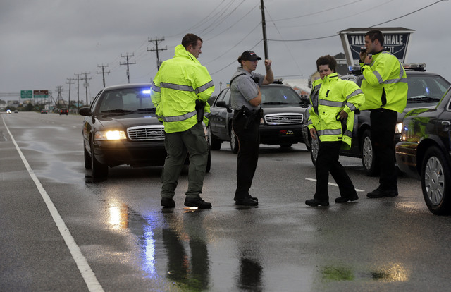 Police officers monitor an area of flooded road on Highway 64 as Hurricane Arthur passes through the area Friday, July 4, 2014, in Nags Head, N.C. (AP Photo/Gerry Broome)
