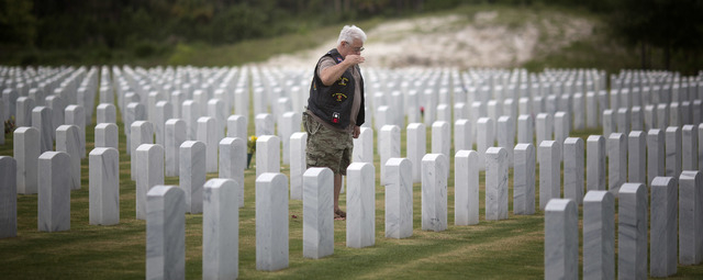 Vietnam veteran Emilo Mourlet pauses to salute his brother's grave at the South Florida National Cemetery in Lake Worth, Fla., Friday, July 4, 2014. He is spending part of the holiday visiting bot ...