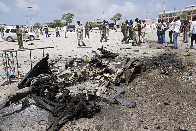 Somali soldiers stand near the wreckage of a suicide car bomb near the Somali parliament in Mogadishu, Somalia, Saturday, July 5, 2014. A Somali police officer says troops have thwarted an attack  ...
