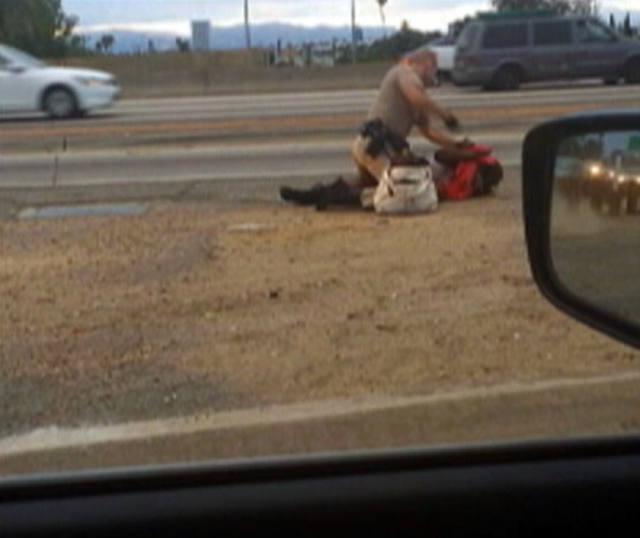 In this July 1, 2014 image made from video provided by motorist David Diaz, a California Highway Patrol officer straddles a woman while punching her in the head on the shoulder of a Los Angeles fr ...