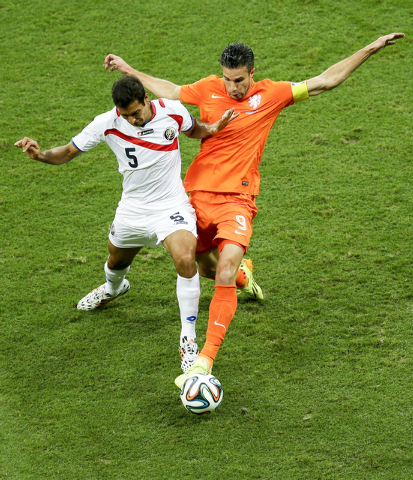 Costa Rica's Celso Borges, left, and Netherlands' Robin van Persie go for the ball during the World Cup quarterfinal soccer match between the Netherlands and Costa Rica at the Arena Fonte Nova in  ...