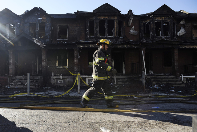 A Philadelphia firefighter walks past burned adjoining homes on Saturday, July 5, 2014, in Philadlephia. Authorities say the fast-moving fire early Saturday has killed four children. Fire departme ...
