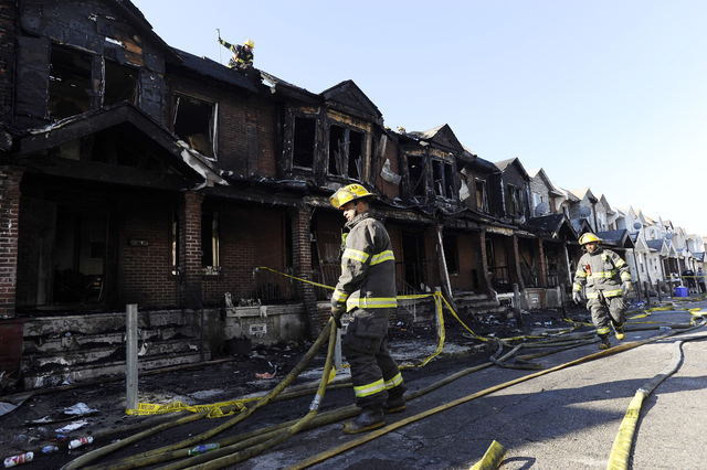 Philadelphia firefighters working on burned row homes on Saturday, July 5, 2014, in Philadlephia. Authorities say the fast-moving fire early Saturday has killed four children. Fire department offi ...