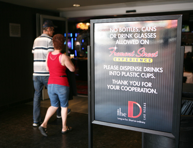 People walk past a sign posted outside the entrance to The D hotel-casino on Fremont Street Experience Thursday, July 17, 2014, in Las Vegas.  A series of liquor ordinances are in effect regulatin ...
