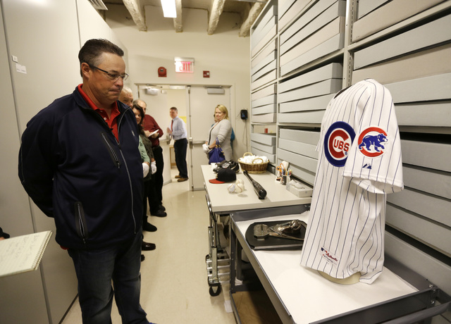 Former Atlanta Braves and Chicago Cubs pitcher Greg Maddux looks the jersey he wore for his 3,000th strikeout during his orientation visit at the Baseball Hall of Fame on Monday, March 24, 2014, i ...