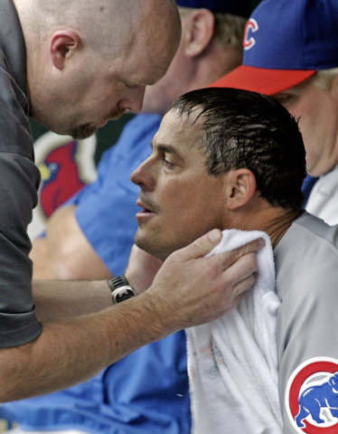 Chicago Cubs starting pitcher Greg Maddux is toweled off in the dugout by the team's trainer during the fourth inning against the St. Louis Cardinals, during their baseball game in St. Louis, Sund ...