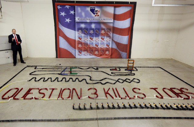 Andy Mathews, president of Nevada Policy Research Institute, stands by a domino demonstration during a news conference at Nevada Policy Research Institute Tuesday, July 22, 2014, in Las Vegas. Th ...