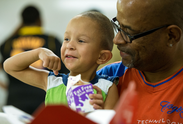 Jakeith Jackson (cq), 3, flexes his muscles while drinking milk with his father, Byron Jackson, right, at Greater Evergreen Missionary Baptist Church, located at 1915 Lexington St., Wednesday, Jun ...