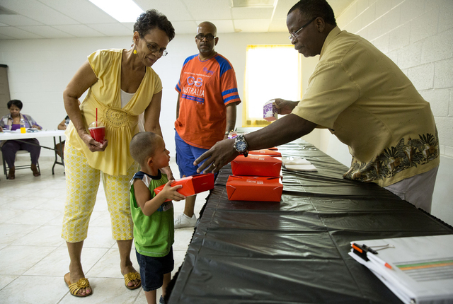 Betty Hardeman (cq), left, helps her grandson, Jakeith Jackson (cq), 3, grab a lunch from Willie Tatum, right, as Jackson's father, Byron Jackson, looks on at Greater Evergreen Missionary Baptist  ...