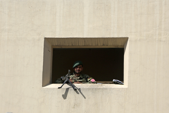 An Afghanistan National Army soldier stands guard at a gate of Camp Qargha, west of Kabul, Afghanistan, Tuesday, Aug. 5, 2014. A man dressed in an Afghan army uniform opened fire Tuesday on foreig ...