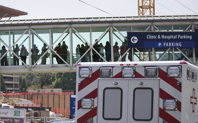 People watch from a bridge as an ambulance transporting Nancy Writebol, an American missionary stricken with Ebola, arrives at Emory University Hospital, Tuesday, Aug. 5, 2014, in Atlanta. Writebo ...