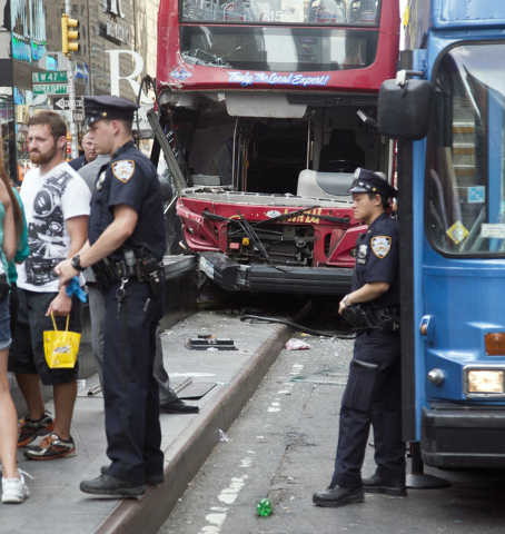 Police guard the scene of a traffic accident involving two double-decker tour buses in New York City's Theater District, Tuesday Aug. 5, 2014.  The Fire Department of New York says 11 people suffe ...