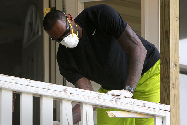 LeBron James knocks the spindles out of a railing at a rehab site on Monday, Aug. 4, 2014, in Akron, Ohio.  James took the controls of a backhoe to help fix up a crumbling house for the family of  ...