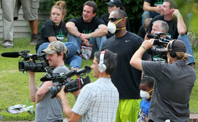 LeBron James and his son, Bryce, look on from a click of camera operators at a rehab site on Monday, Aug. 4, 2014, in Akron, Ohio.  James took the controls of a backhoe to help fix up a crumbling  ...