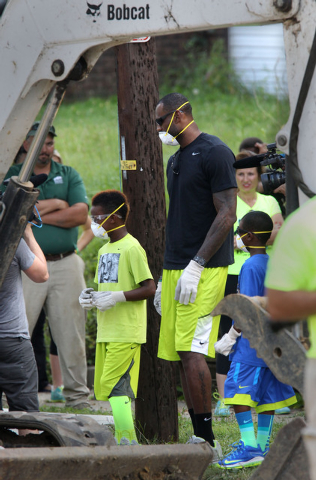 LeBron James and his sons, LeBron Jr., left,  and Bryce, head to the heavy equipment at a rehab site on Monday, Aug. 4, 2014, in Akron, Ohio.  James took the controls of a backhoe to help fix up a ...