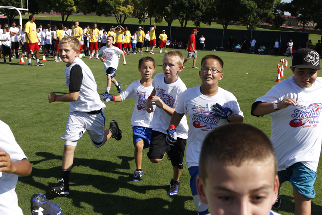 Children run to their assigned practice areas during the  Royal Purple Las Vegas Bowl Youth Football Clinic at Bill "Wildcat" Morris Rebel Park at UNLV Tuesday, Aug. 5, 2014. (Erik Verduzco/Las Ve ...