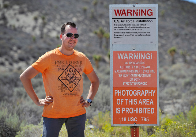 Floris Otten, of The Netherlands, stands by a warning sign as he poses for a photograph at the perimeter of the well guarded military installation on Tuesday, Aug. 5, 2014. Otten was a part of a s ...