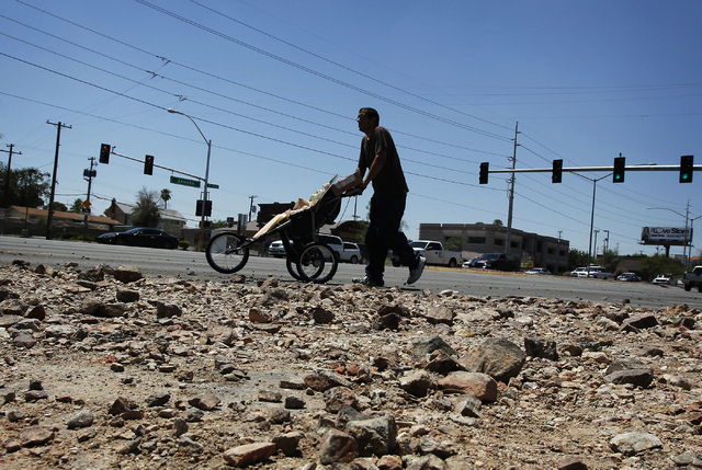 A pedestrian makes his way past a large deposit of debris at the intersection of Sahara and Richfield the day after flash floods swept through Las Vegas on Tuesday, Aug. 5, 2014. (Jason Bean/Las V ...