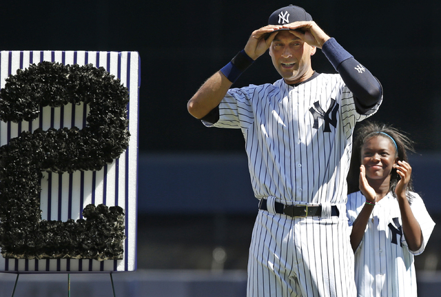 A youngster applauds as New York Yankees shortstop Derek Jeter (2) adjusts his cap after tipping it to the crowd during a pregame ceremony honoring the Yankees captain who is retiring at the end o ...