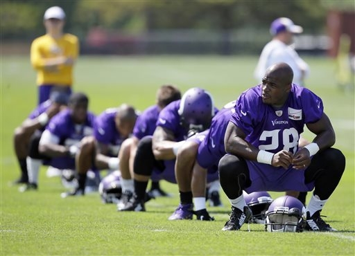 In this July 26, 2014, file photo,Minnesota Vikings running back Adrian Peterson, right, stretches during NFL football training camp in Mankato, Minn. After a day of public pressure from angry fan ...
