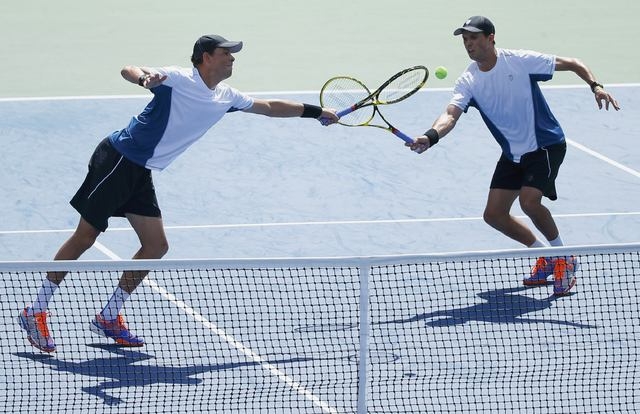 Bob Bryan (L) and his brother Mike Bryan of the U.S. reach for the ball while playing Marcel Granollers and Marc Lopez of Spain during their men's doubles final match at the 2014 U.S. Open tennis  ...