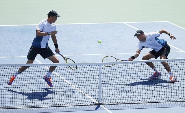 Bob Bryan (L) of the U.S. watches as his brother Mike Bryan returns the ball to Marcel Granollers and Marc Lopez of Spain during their men's doubles final match at the 2014 U.S. Open tennis tourna ...