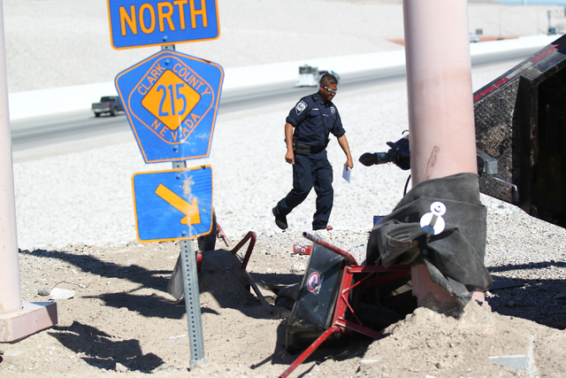 A Nevada Highway Patrol officer investigates a crash involving two landscaping trucks that caused one to catch fire at the Summerlin Parkway and 215 Beltway intersection in Las Vegas on Wednesday, ...