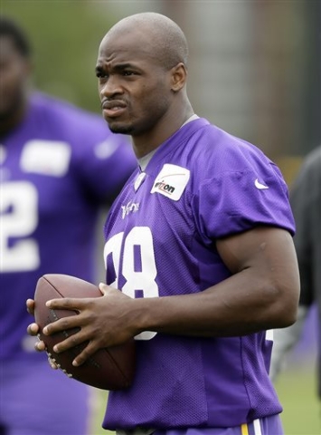 In this July 28, 2014, file photo,Minnesota Vikings running back Adrian Peterson looks on during NFL football training camp in Mankato, Minn. After a day of public pressure from angry fans and co ...