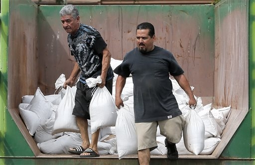 Julio Valenzuela Jr. and Julio Valenzuela Sr. take free sandbags to protect their homes, Tuesday, Sept. 16, 2014, in Mesa, Ariz. Phoenix-area residents are filling sandbags in anticipation of the ...