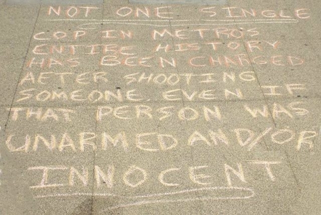 Four protesters have been charged in connection with messages written in chalk outside the Metropolitan Police Departments headquarters and in front of the Regional Justice Center. The one above ...
