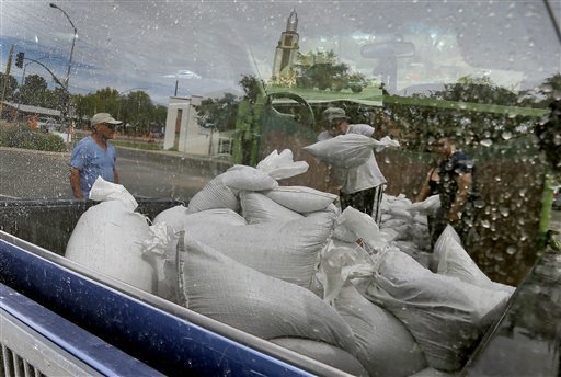 Mesa residents, reflected in a truck window, take free sandbags to protect their homes, Tuesday, Sept. 16, 2014, in Mesa, Ariz. Phoenix-area residents are filling sandbags in anticipation for the  ...