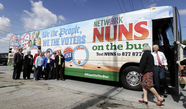 Vice President Joe Biden steps off the Nuns on the Bus tour bus with Sister Simone Campbell during a stop, Wednesday, Sept. 17, 2014, in Des Moines, Iowa. (AP Photo/Charlie Neibergall)