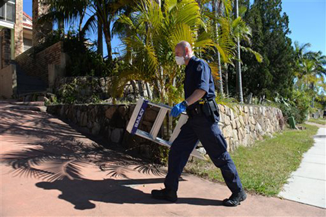 A police officer searches a house in Mount Gravatt, Brisbane, Australia, Thursday, Sept. 18, 2014. Australian police detained 15 people on Thursday in a major counterterrorism operation, saying i ...