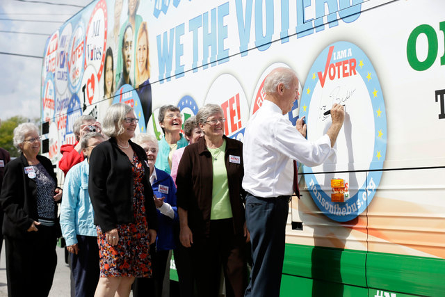 Vice President Joe Biden signs the Nuns on the Bus tour bus during a stop, Wednesday, Sept. 17, 2014, in Des Moines, Iowa. (AP Photo/Charlie Neibergall)