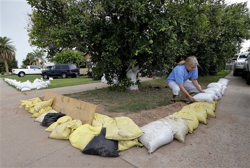 Gayle Peterson stacks sandbags to protect her home, Tuesday, Sept. 16, 2014, in Mesa, Ariz. Phoenix-area residents are filling sandbags in anticipation of the remnants of Category 3 Hurricane Odil ...