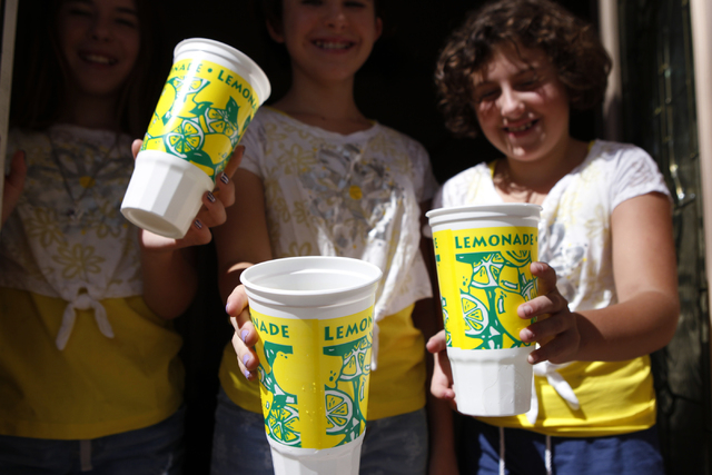 Sisters Jenna Rocheleau, from left, 12, her twin Jordan 12, and Stacy, 10, pose for a portrait holding the lemonade cups they use to sell their lemonade at their home in Henderson Saturday, Sept.  ...